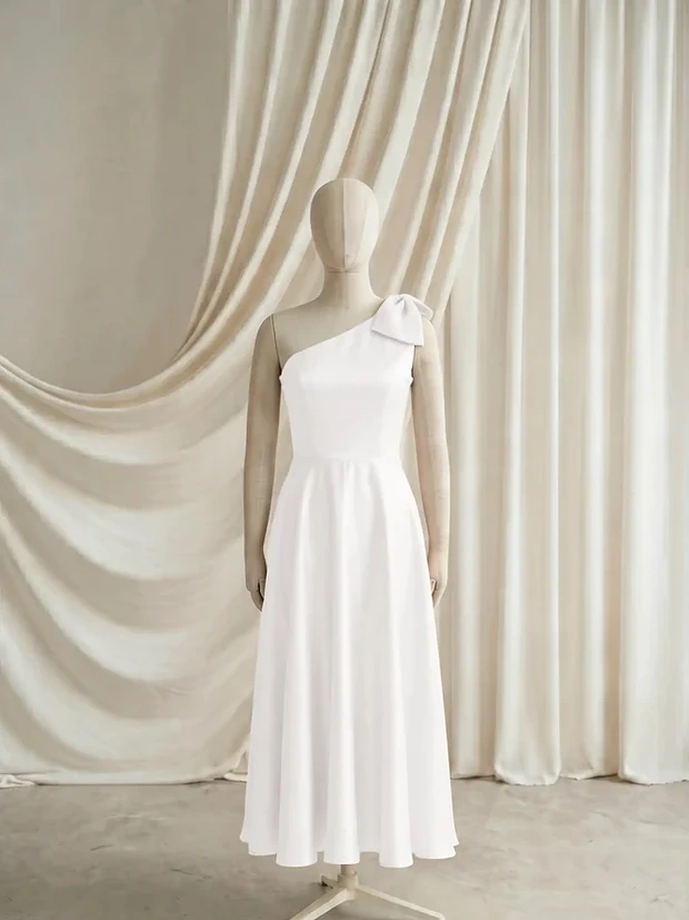 Mara Ivory satin junior bridesmaid dress by TH&TH — front, showing the one-shoulder bow
