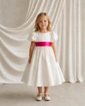 Poppy ivory matte satin flower girl dress by TH&TH with a removable cerise satin sash tied in a bow, front view