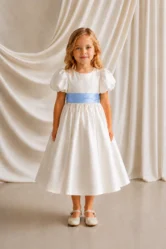Poppy ivory matte satin flower girl dress by TH&TH with a removable dusty blue satin sash tied in a bow, front view